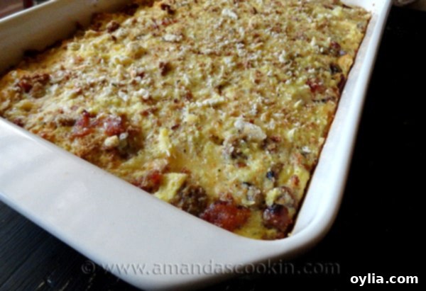 A close-up view of the Herbed Breakfast Stuffing Casserole, highlighting the individual components like savory sausage, crumbled bacon, and melted Gouda cheese, all bound by fluffy eggs.