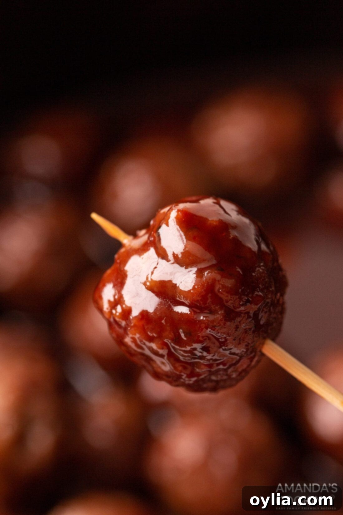 Sweet and Tangy Grape Jelly Meatballs 3 holding grape jelly meatball with a toothpick