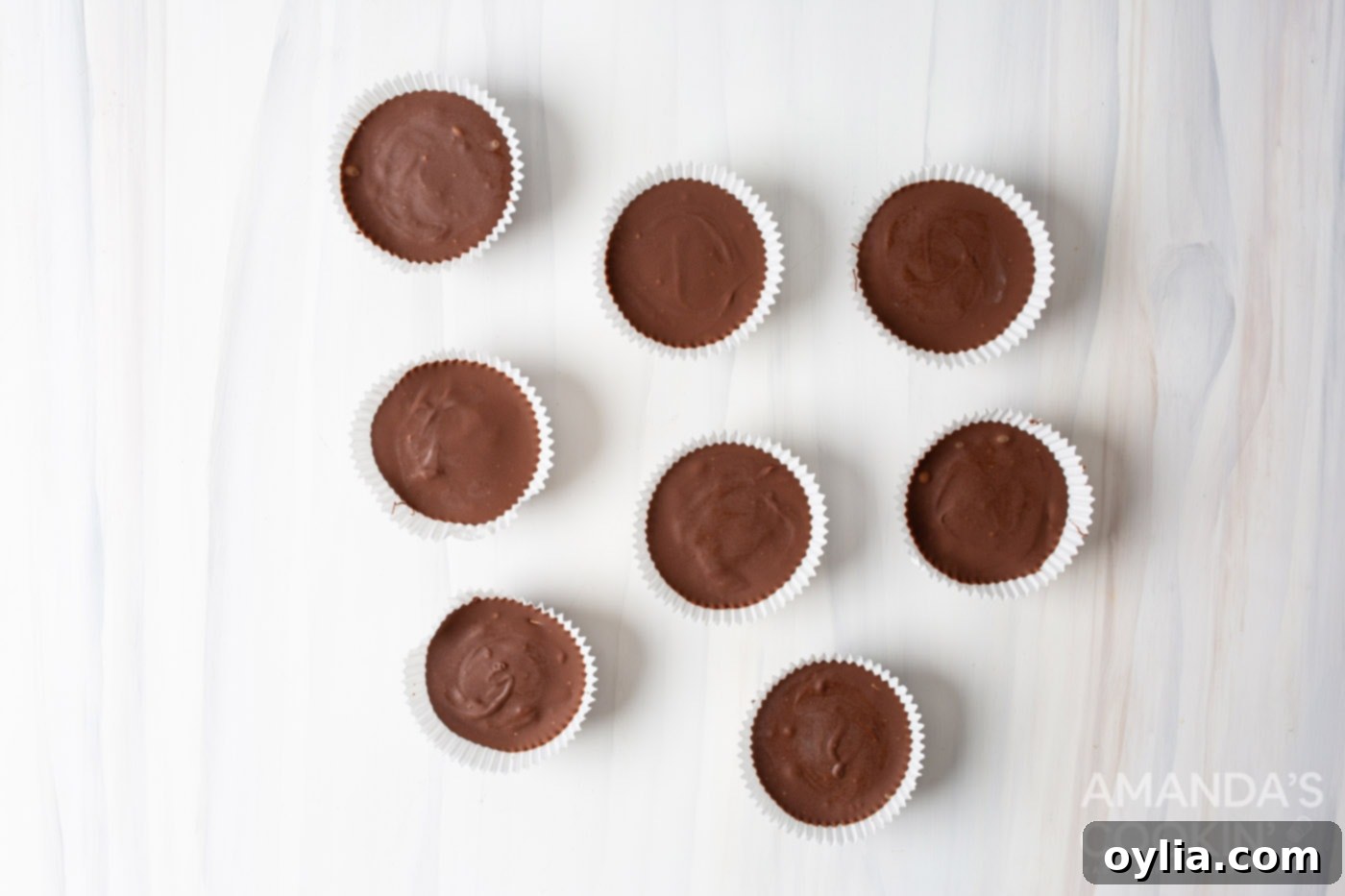 Several homemade peanut butter cups setting in cupcake liners, ready for chilling.