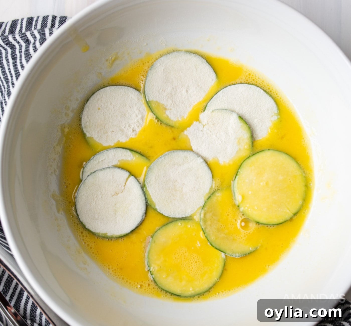 dredging flour coating zucchini slices in egg