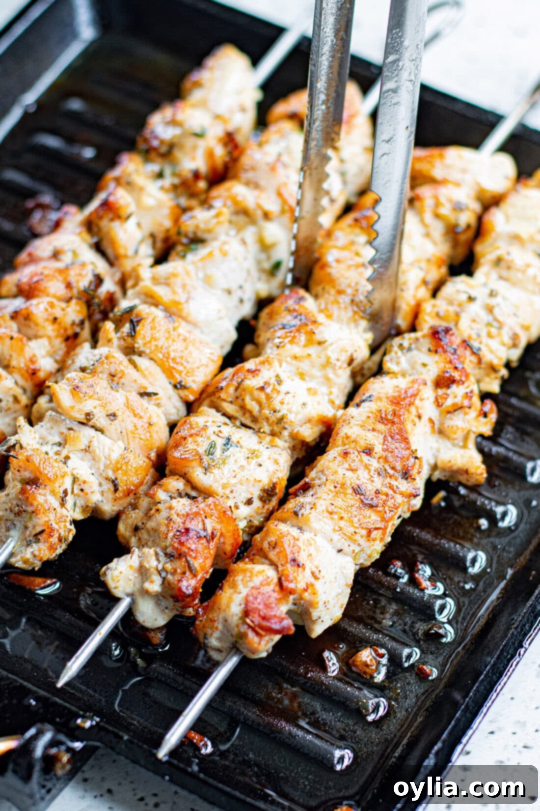 Close-up of Greek Chicken Kabobs being lifted off the grill with tongs