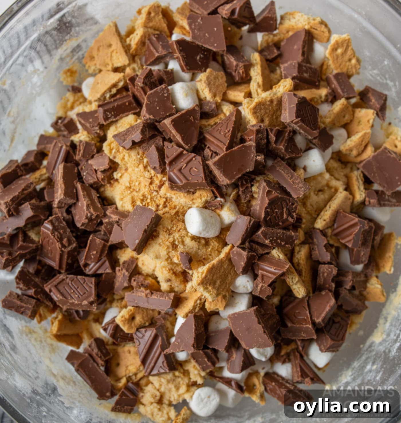 Chocolate chunks, graham crackers, and mini marshmallows being folded into the cookie dough