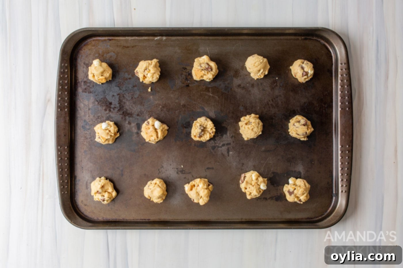 S'mores cookie dough balls neatly arranged on a baking pan, ready for the oven