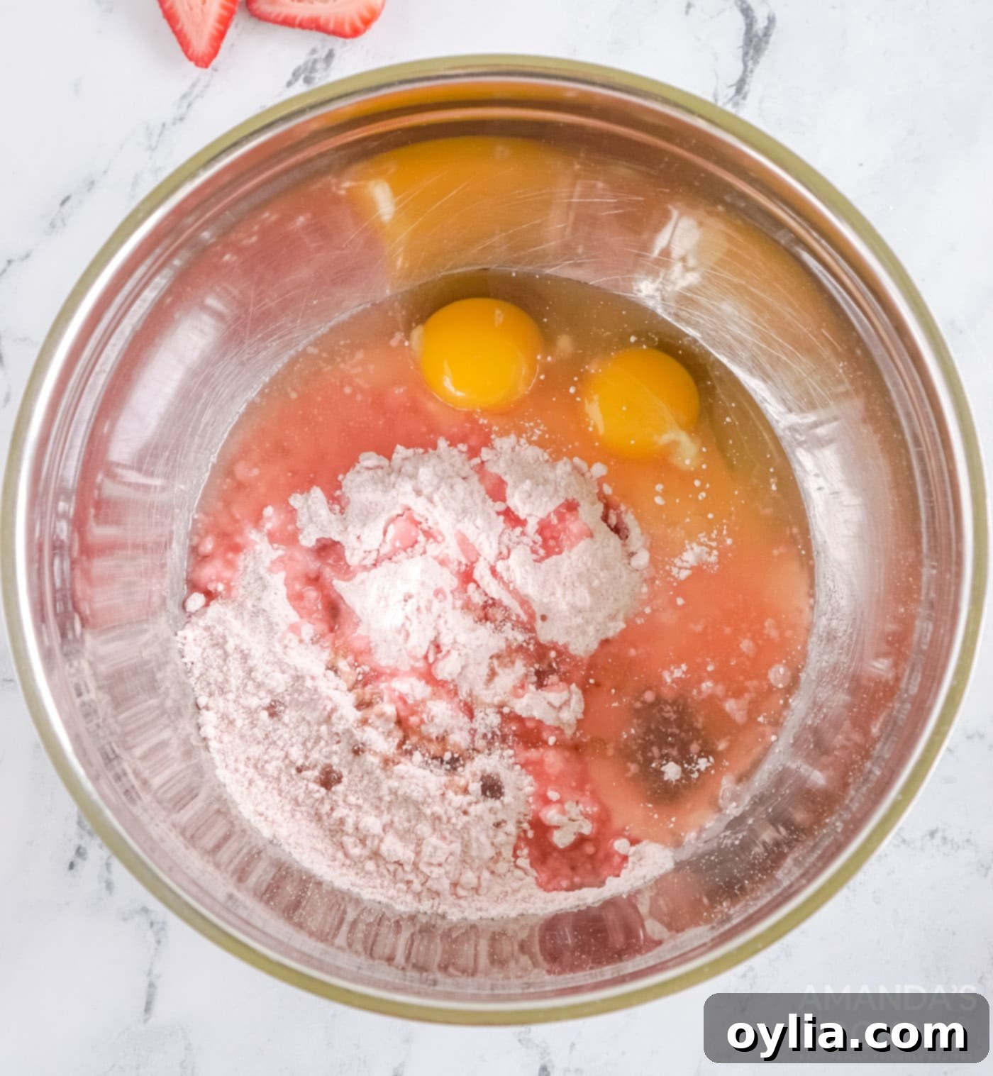 Eggs, oil, and strawberry cake mix being combined in a bowl for cookie dough.