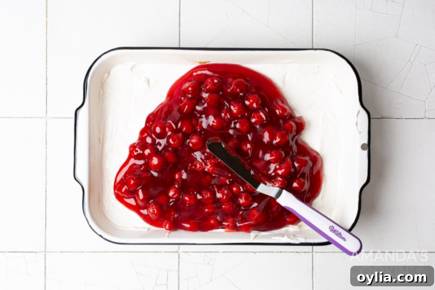 cherry pie filling on top of cream cheese mixture in baking pan