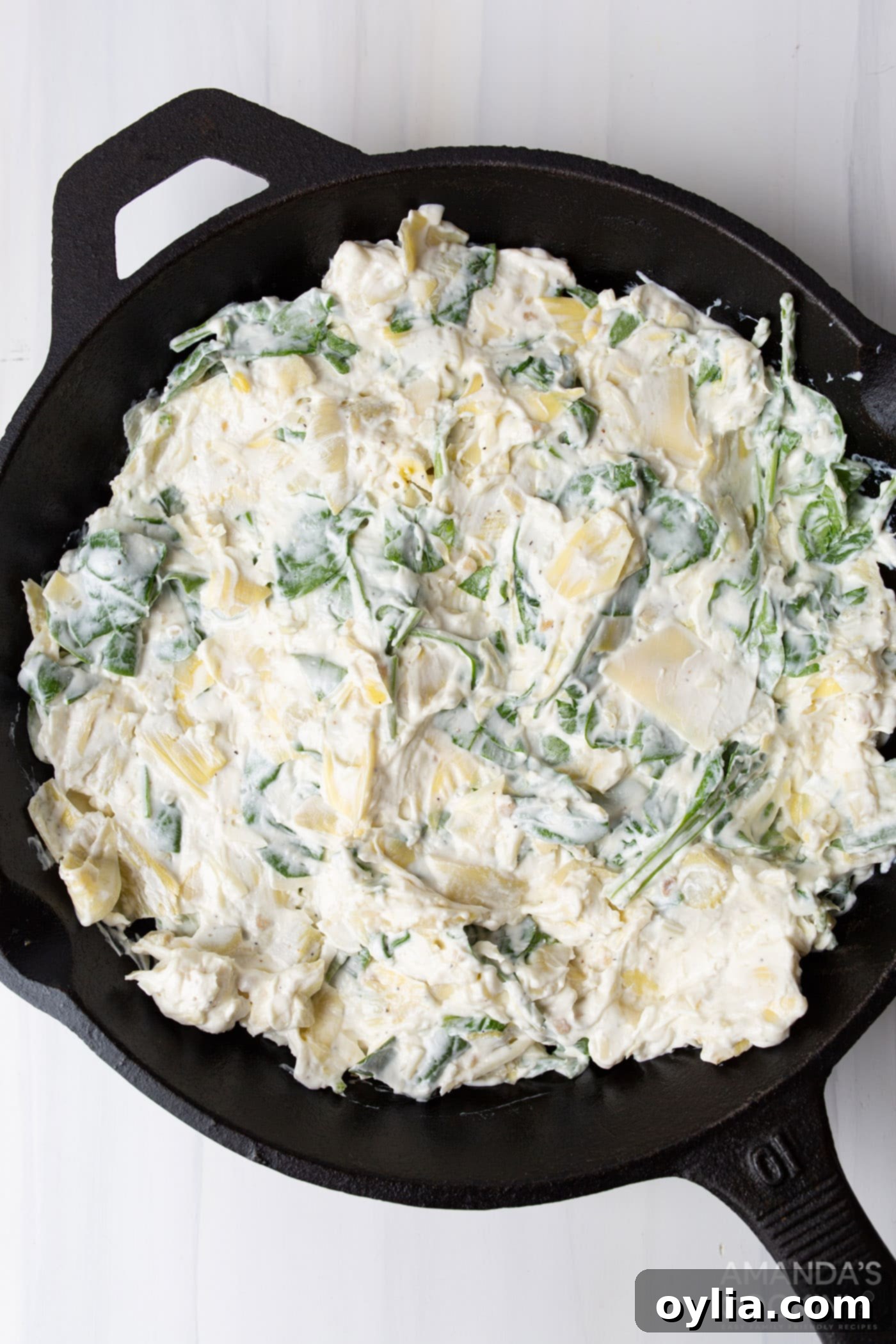 Spinach artichoke dip ingredients in a skillet