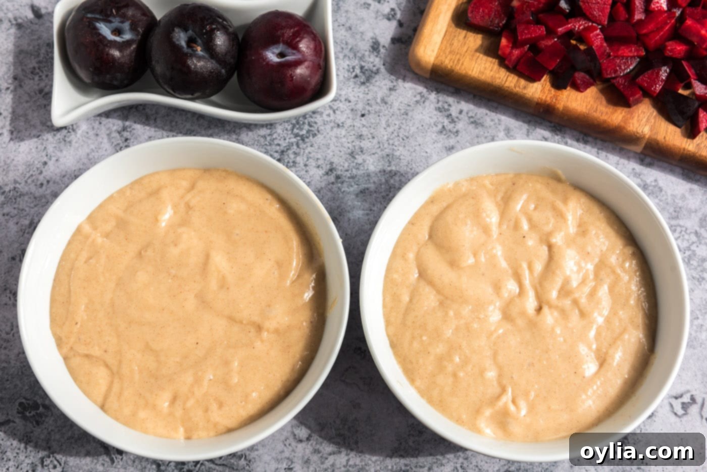 Muffin batter evenly divided into two separate bowls, ready for the plum addition.
