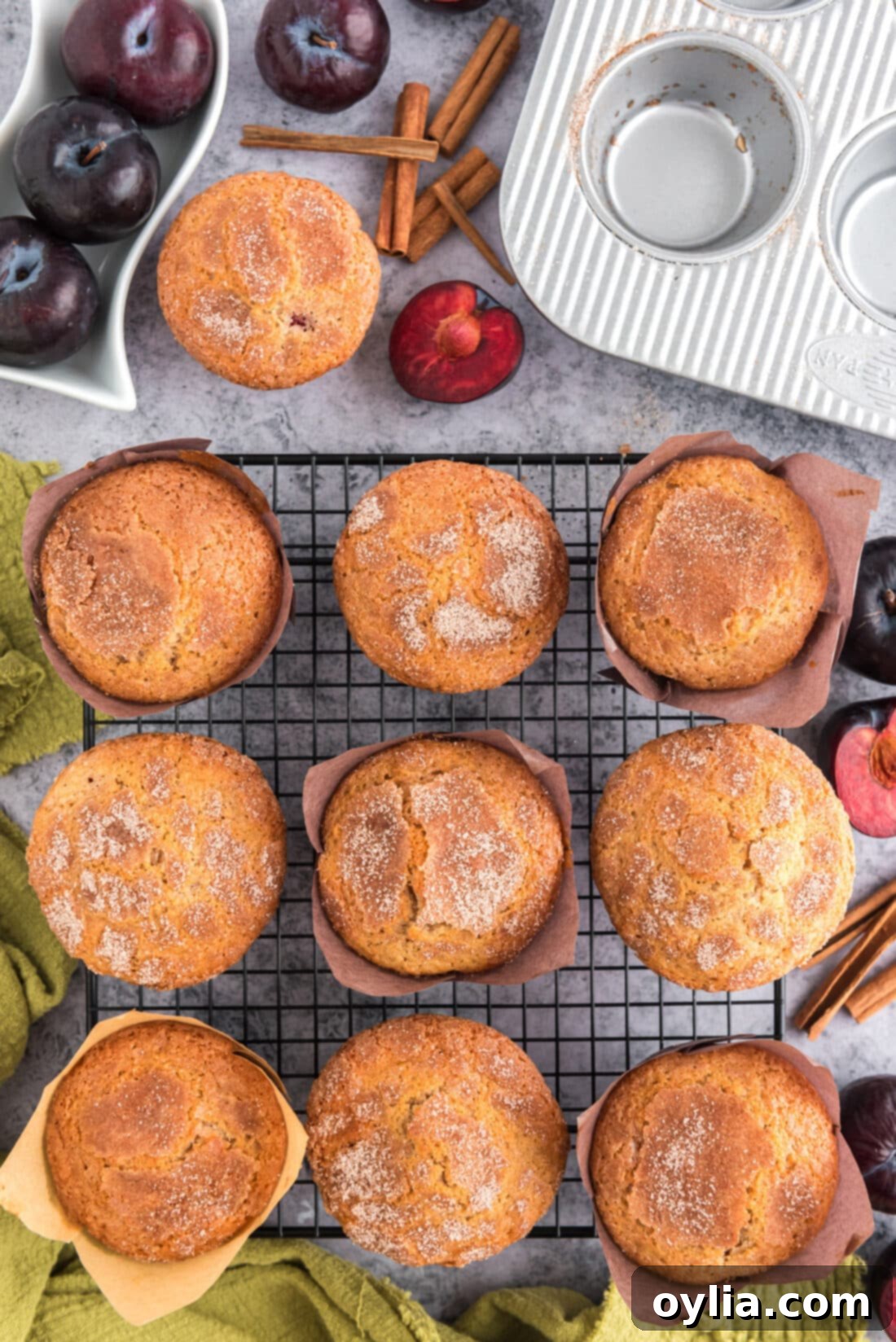 A stack of golden brown Sugar Crusted Plum Muffins resting on a wire rack to cool, showcasing their beautiful tops.