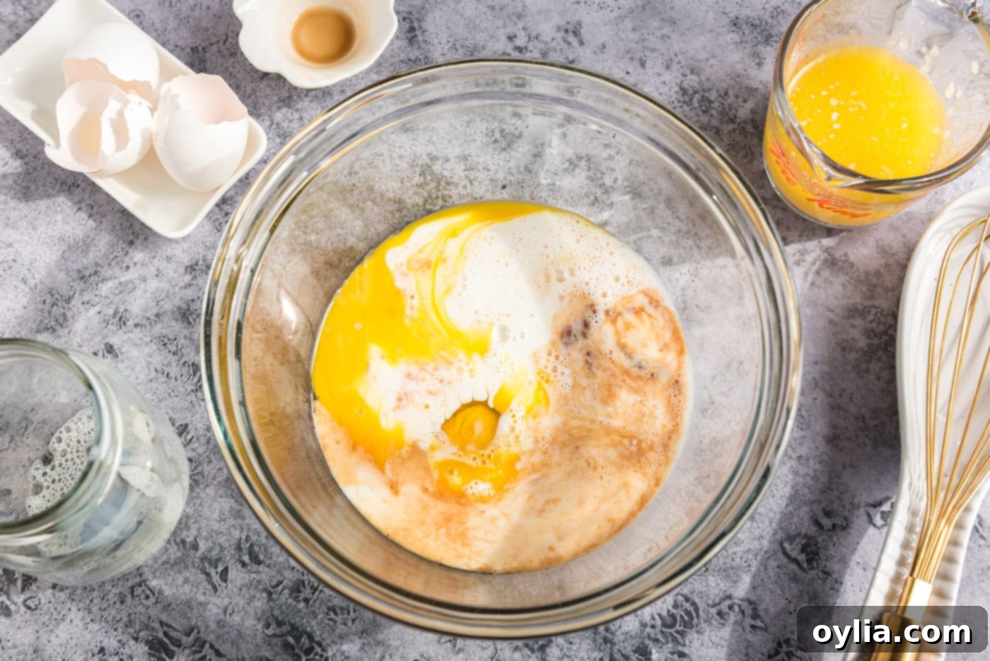 Bowl with eggs, vanilla extract, milk, and melted butter, ready to be whisked for muffin batter.