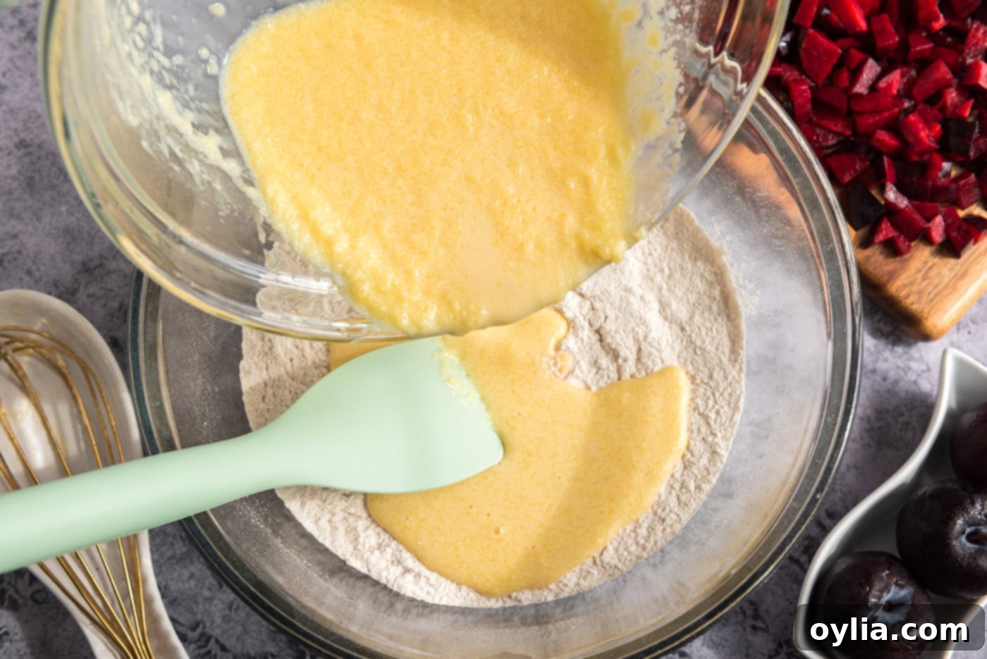 Pouring the whisked egg mixture into the bowl of dry ingredients for muffin batter.