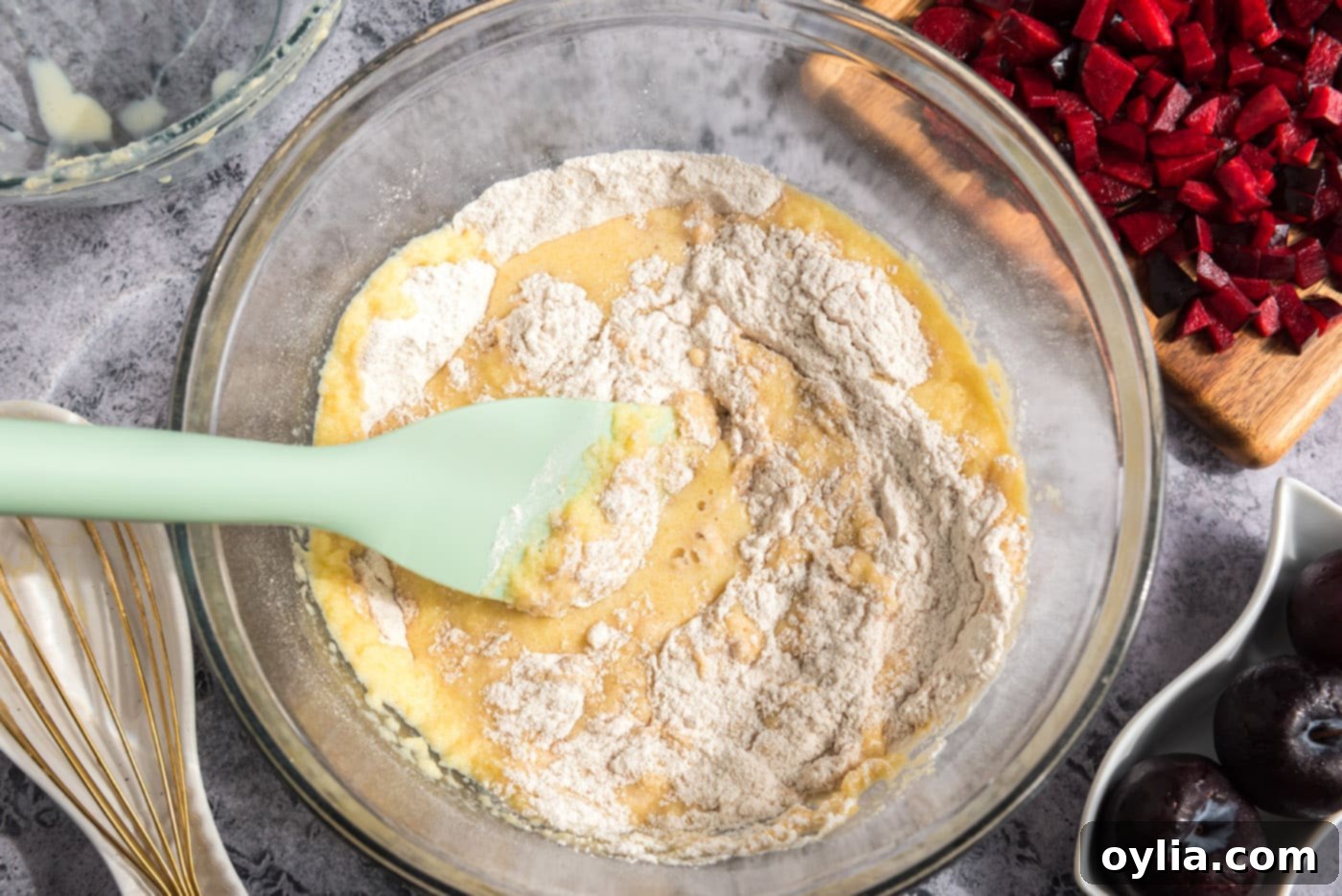 A rubber spatula gently folding the wet and dry ingredients together in a large mixing bowl to form muffin batter.
