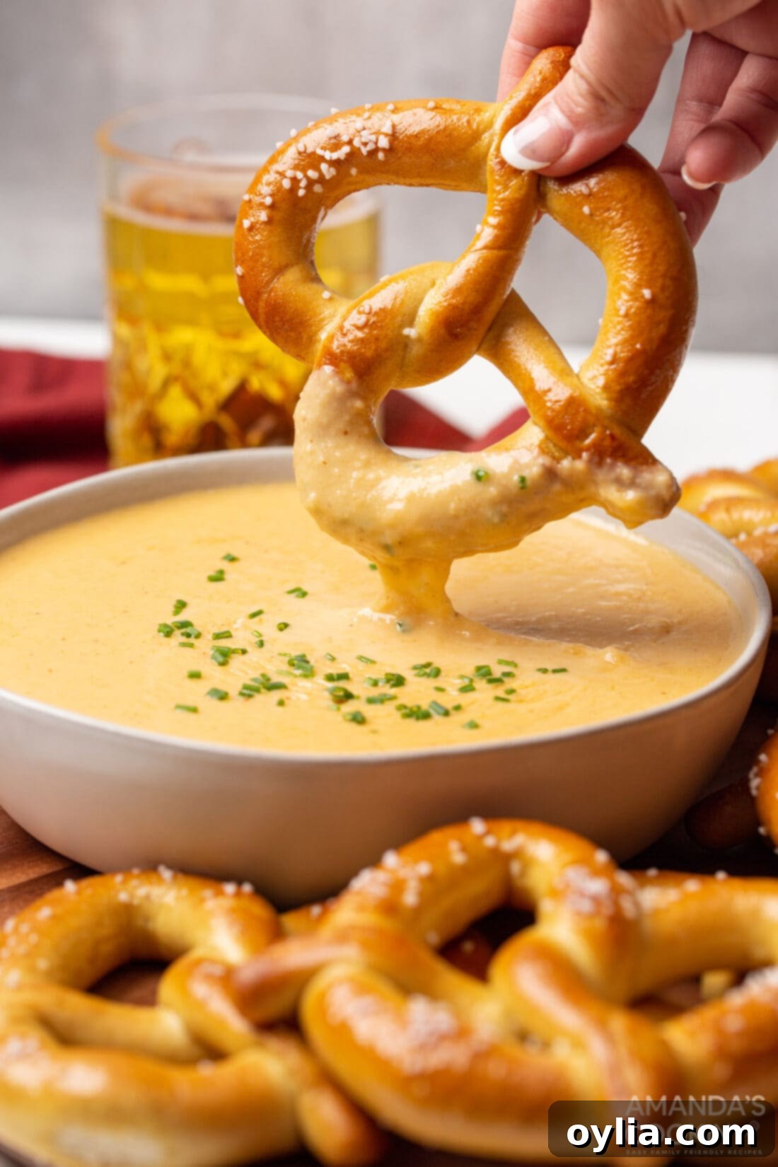 dipping pretzel in beer cheese dip, showcasing the creamy texture and perfect pairing