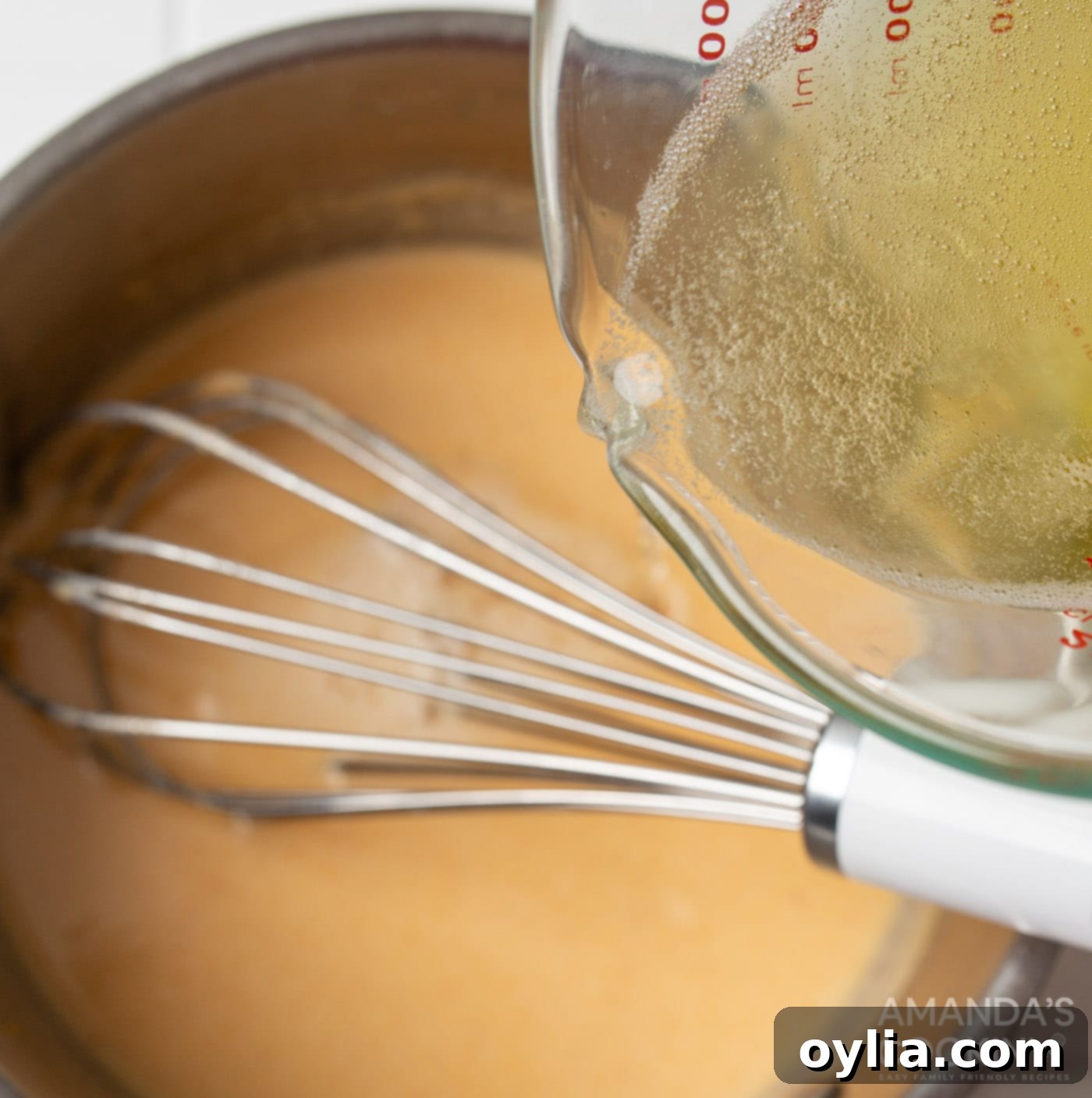 pouring beer into roux mixture for beer cheese dip