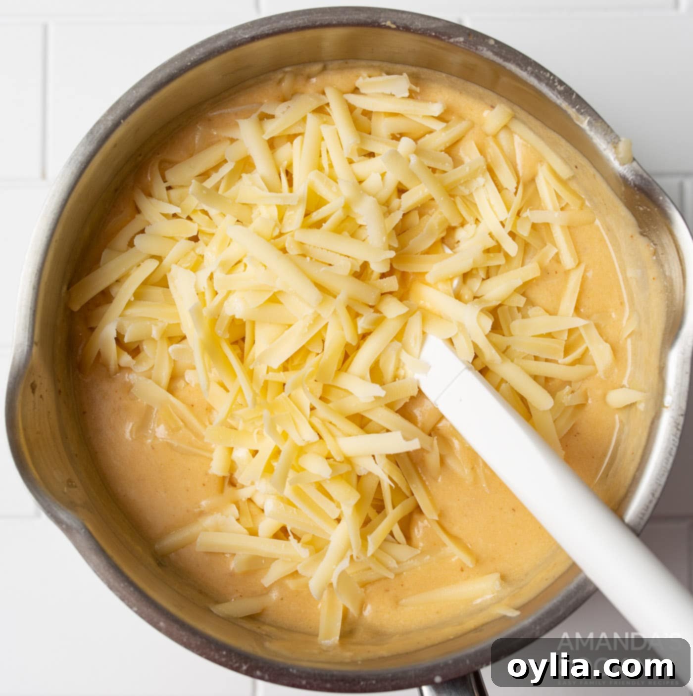 shredded cheese being stirred into beer cheese dip until smooth