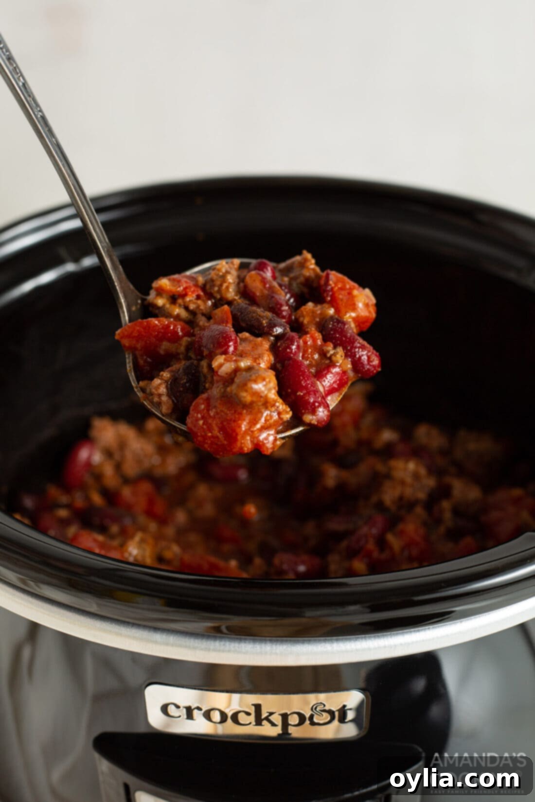 Slow Cooker Comfort Chili 2 A steaming bowl of hearty Crockpot Chili, garnished with fresh cilantro and a dollop of sour cream, sitting on a rustic wooden surface, inviting you to enjoy this comforting meal.