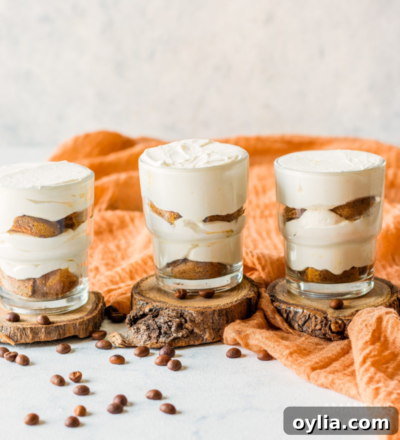A close-up of a cup with finished layers of mascarpone cheese mixture and ladyfingers, ready for chilling.