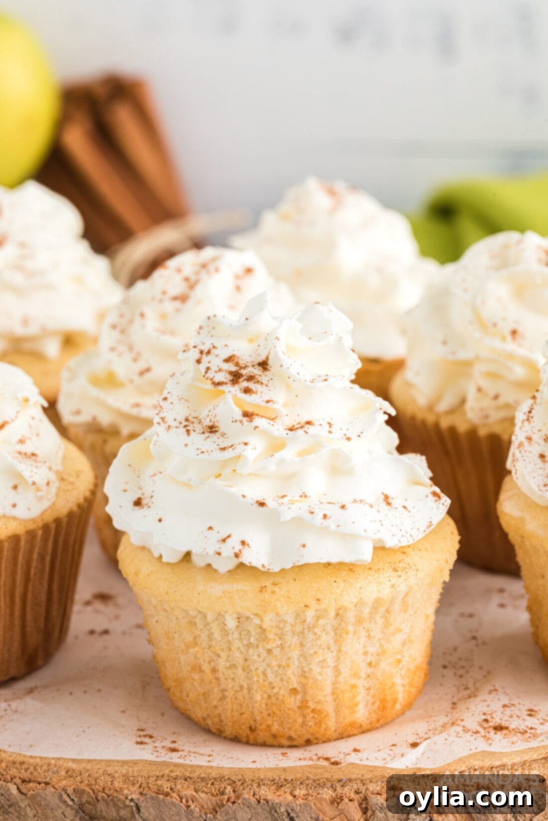 A beautifully frosted apple pie cupcake, garnished with a sprinkle of cinnamon, ready to be enjoyed.