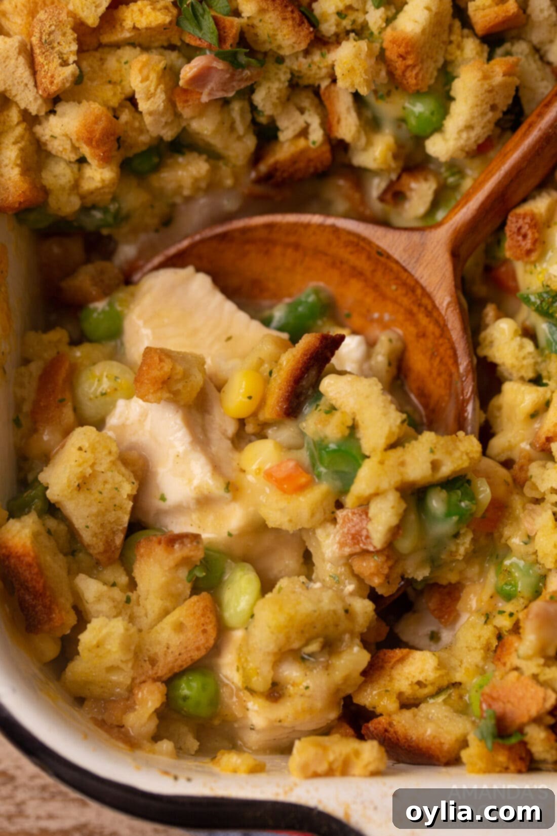 wooden spoon in dish of Chicken Stuffing Casserole, showcasing a golden-brown, hearty meal