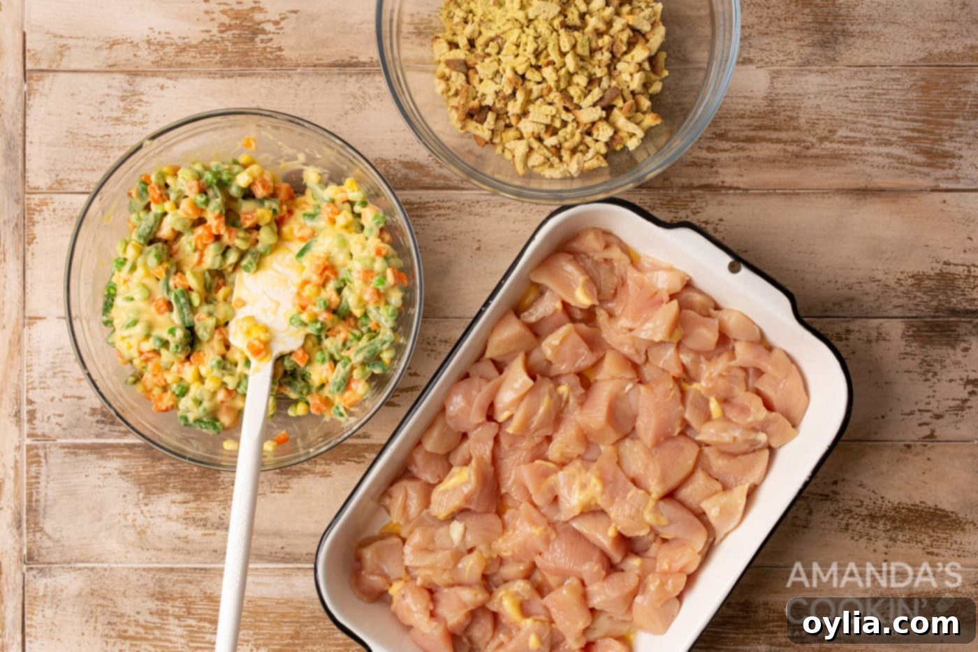 diced chicken in a casserole dish with veggies and stuffing, ready for baking