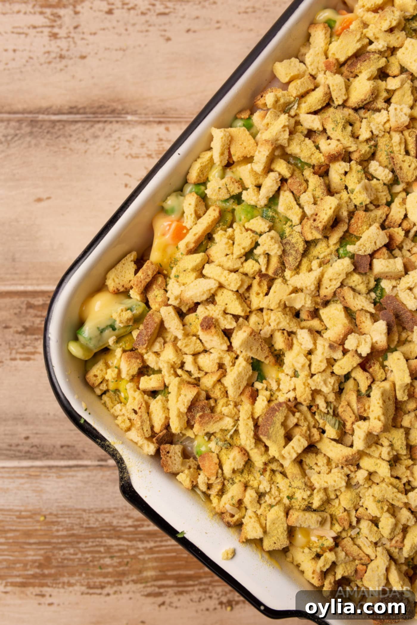 dried bread cubes on top of veggies and chicken in a casserole dish, prior to baking