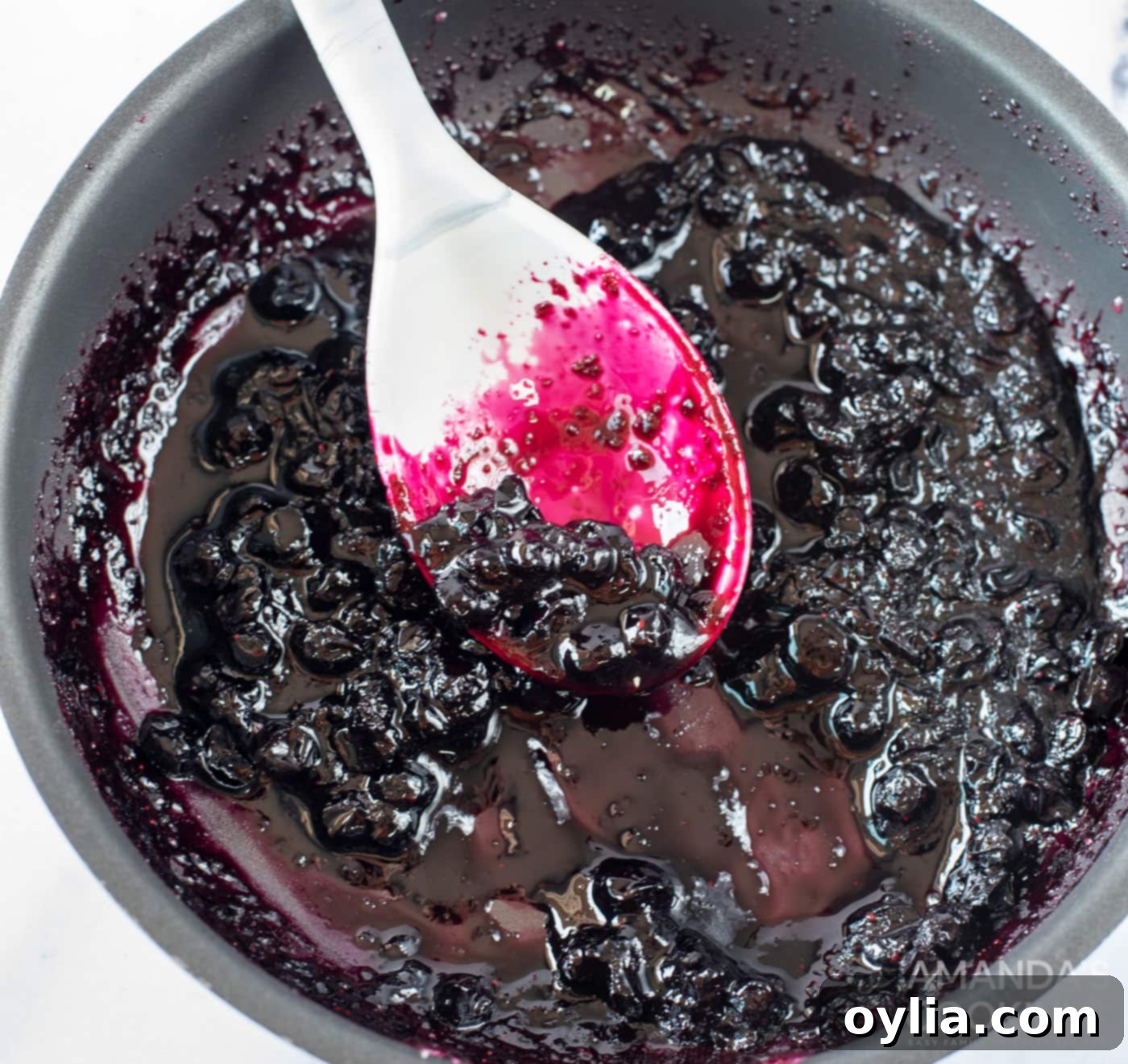 Blueberry mixture simmering in a saucepan, thickening into a syrup