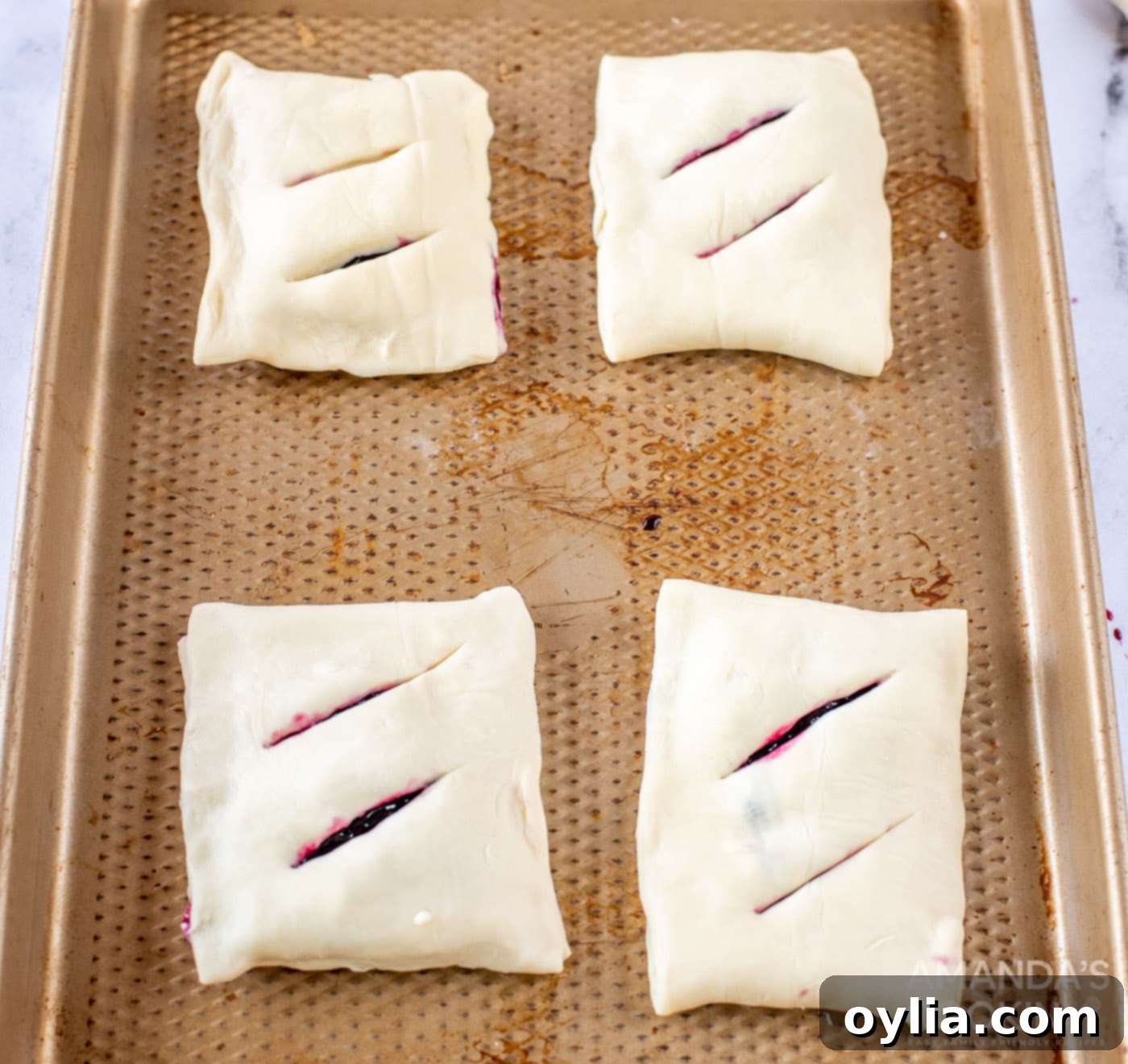 Lemon blueberry hand pies baking on a sheet, turning golden brown