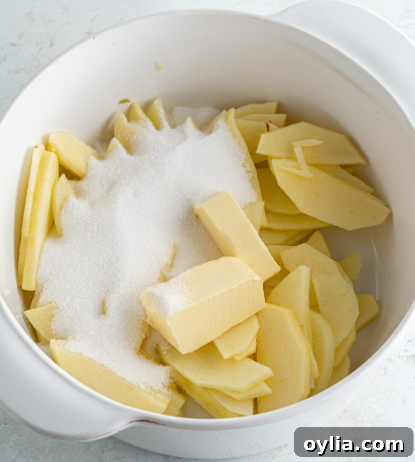 sugar and butter in a bowl with sliced apples