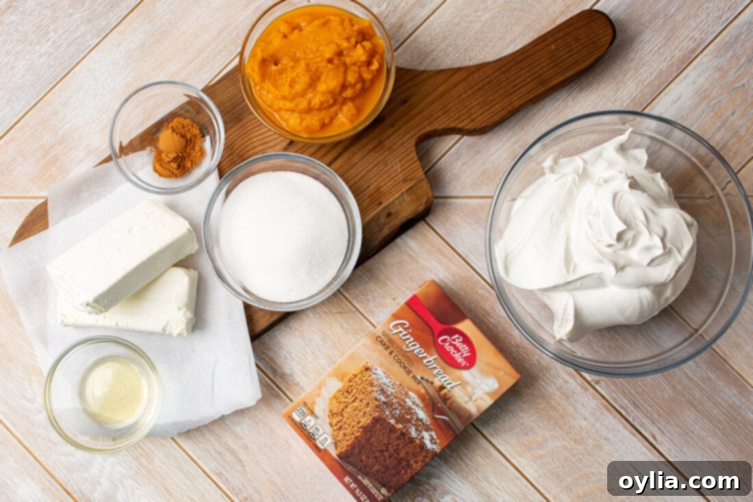 A selection of ingredients laid out on a table for making pumpkin trifle, including cream cheese, pumpkin puree, gingerbread mix, and whipped topping.
