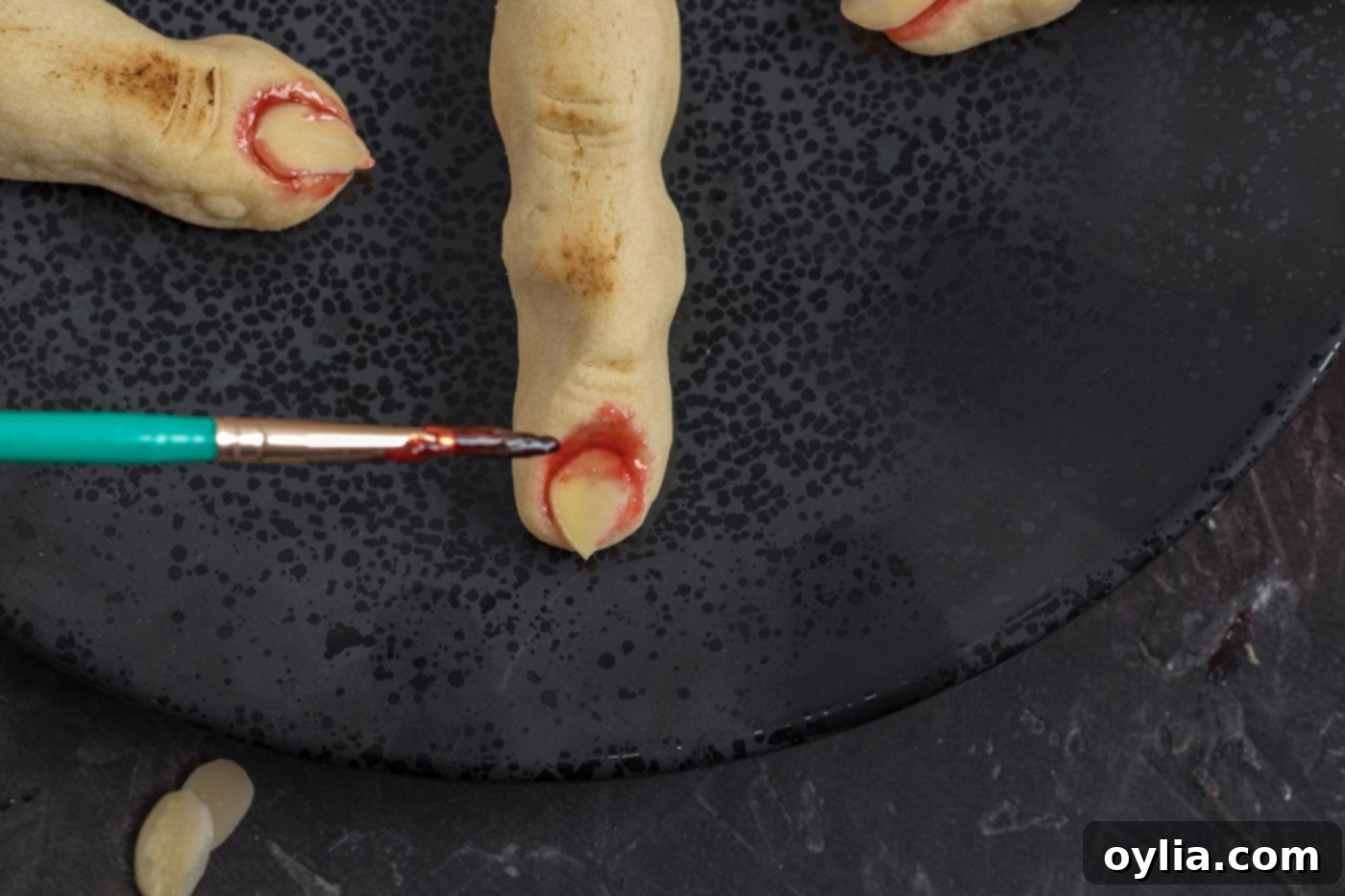 painting strawberry jam on witch finger cookies
