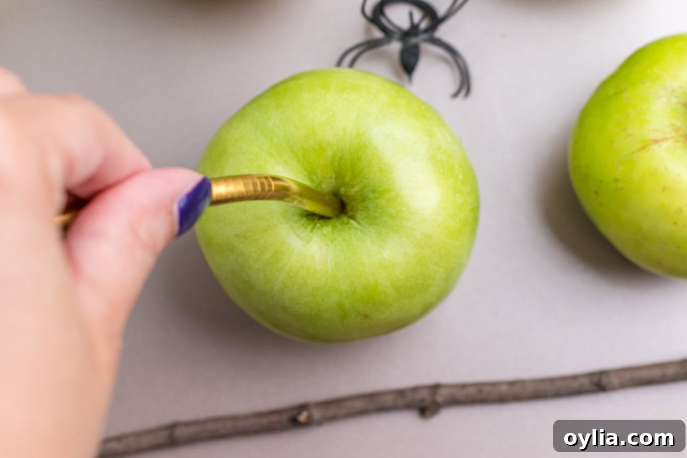 sticking a metal straw into green apple