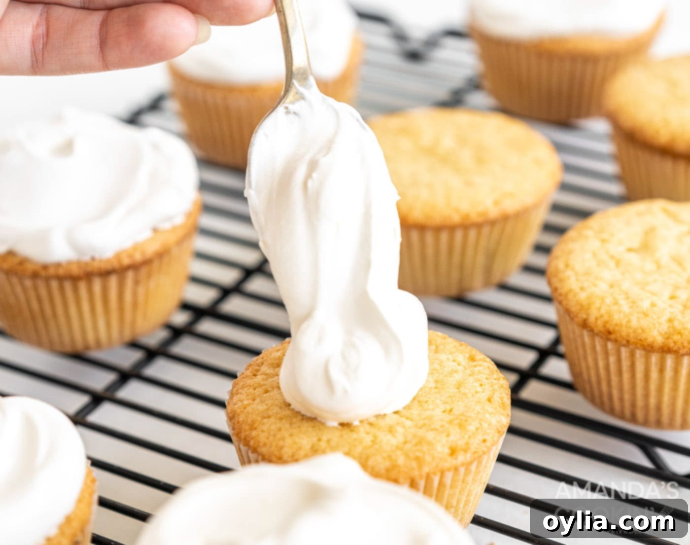 spooning whipped cream on top of pound cake cupcakes