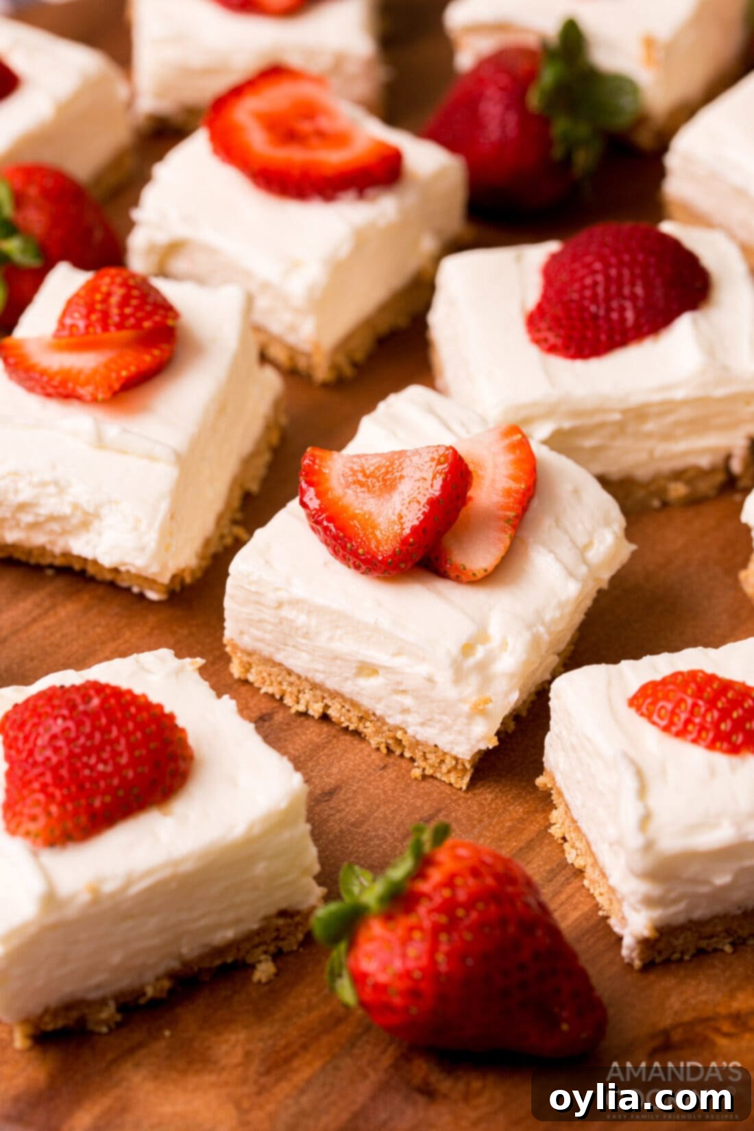 Decadent No Bake Cheesecake Bars garnished with fresh sliced strawberries on a wooden board