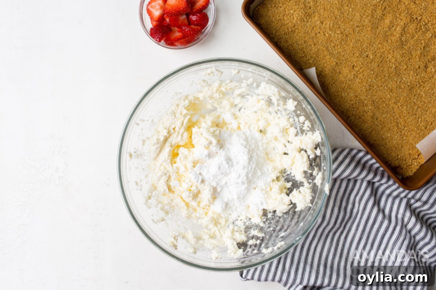 Smooth, softened cream cheese being beaten with powdered sugar and vanilla extract in a large mixing bowl for the no-bake filling