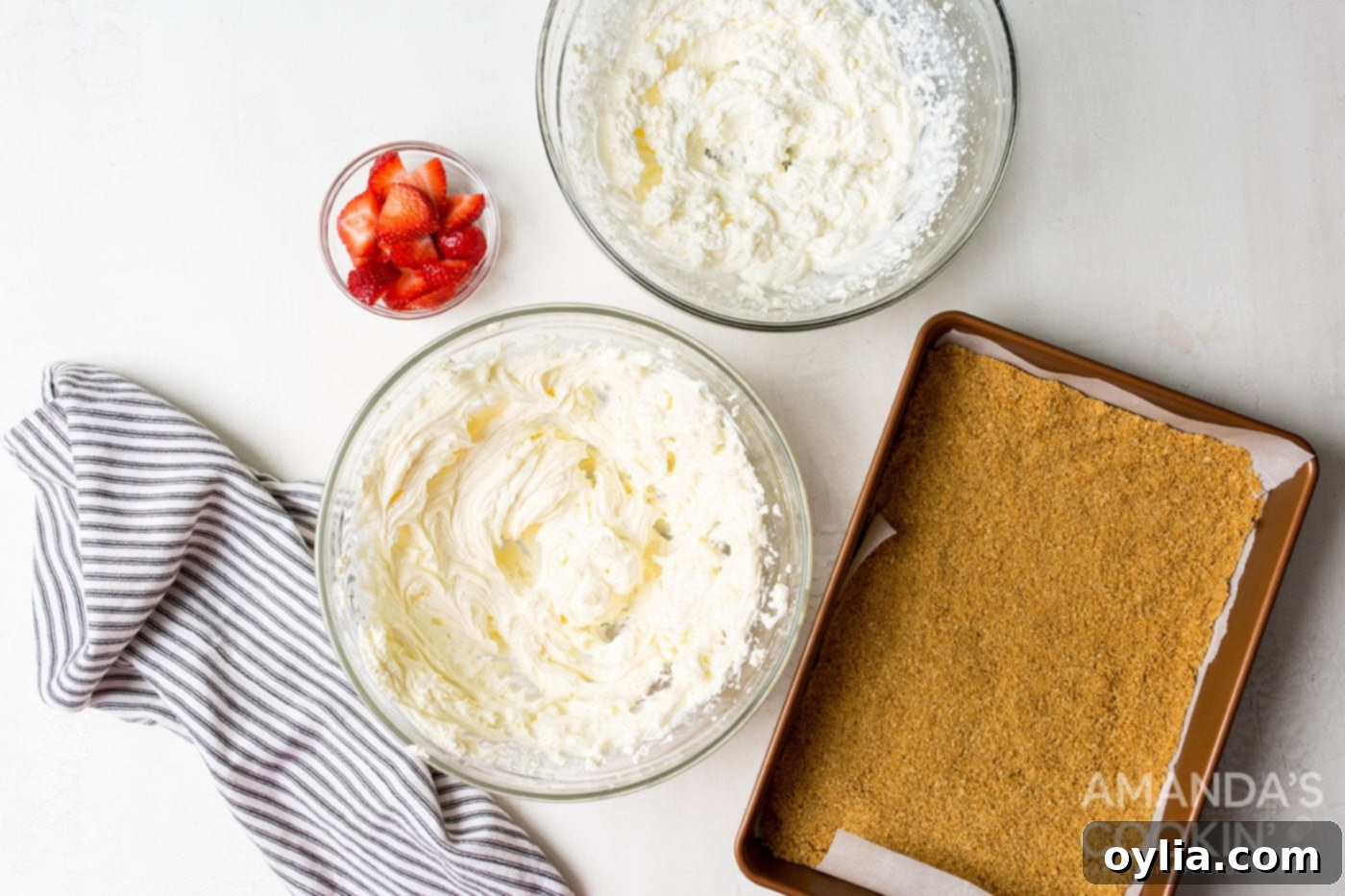 Separate bowls showing stiffly whipped heavy cream and the fluffy cream cheese mixture, ready to be combined