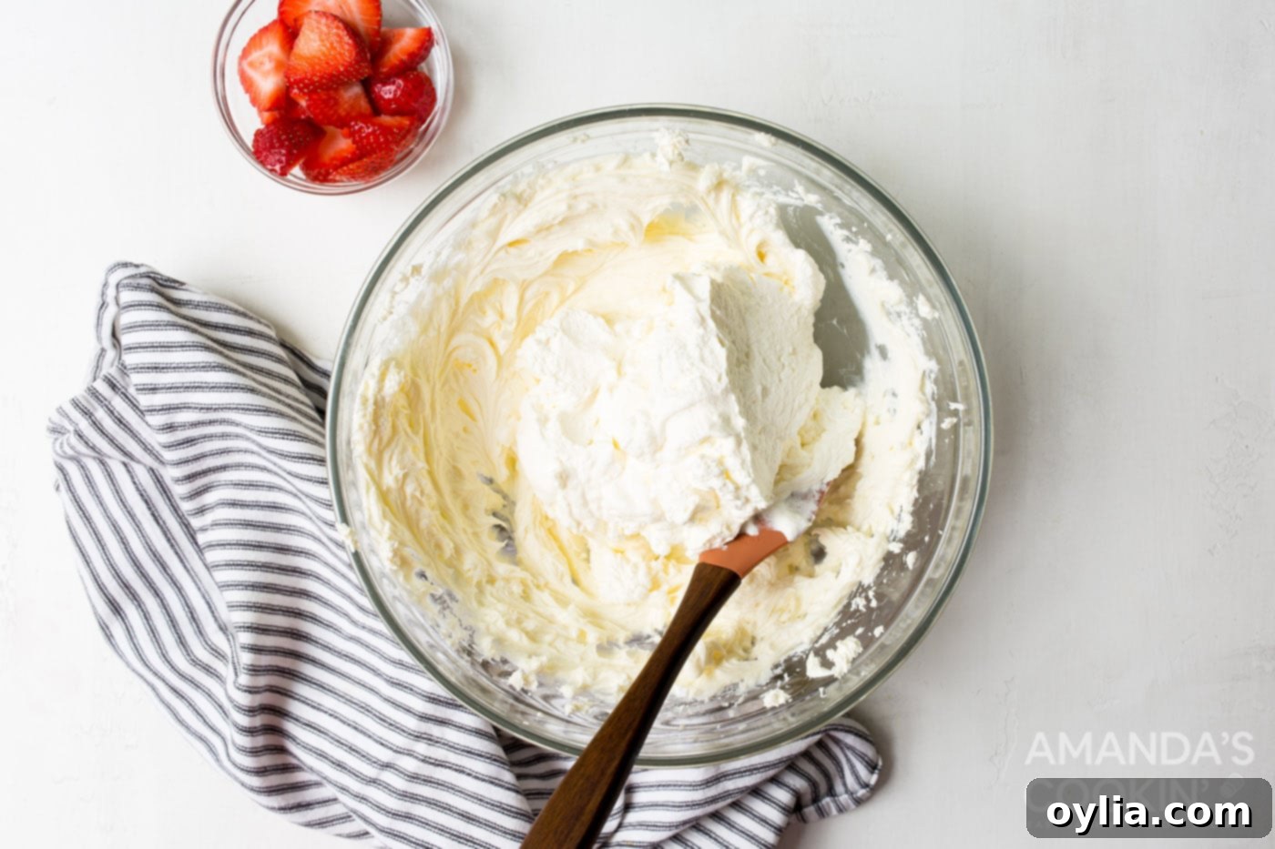 Gently folding light whipped cream into the rich cream cheese filling with a rubber spatula