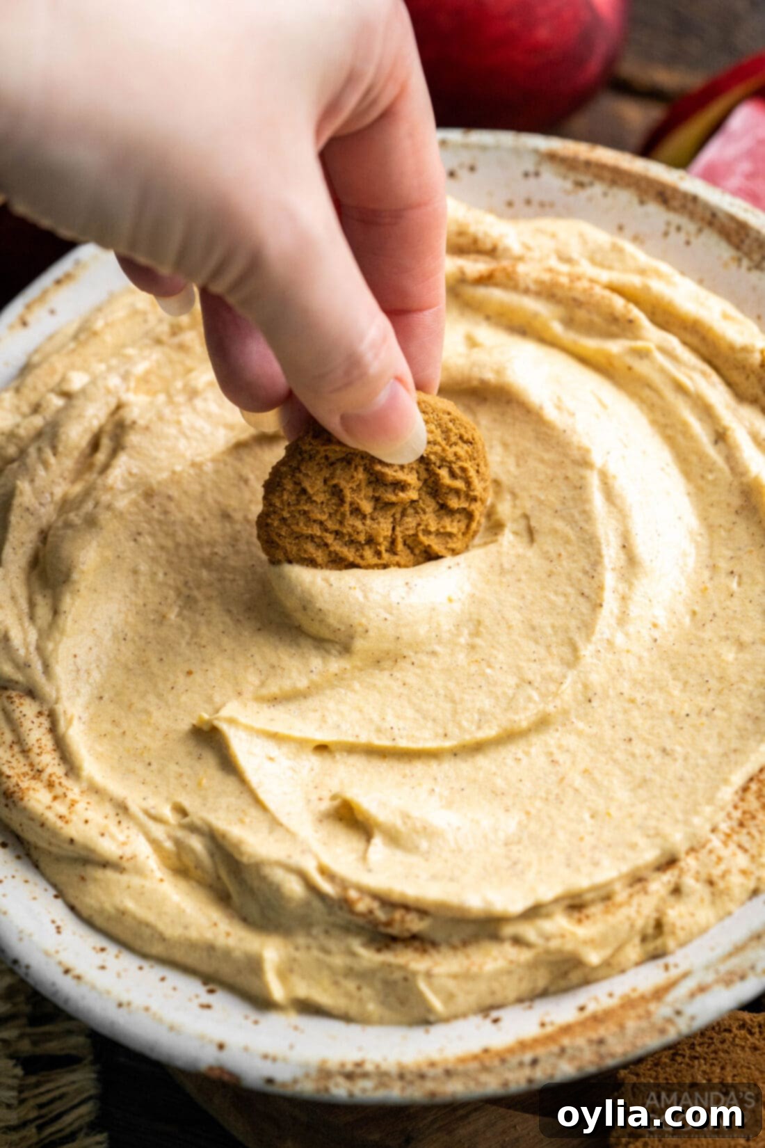 A delicious cookie being dipped into a bowl of creamy Pumpkin Pie Dip, highlighting its perfect texture for dipping.