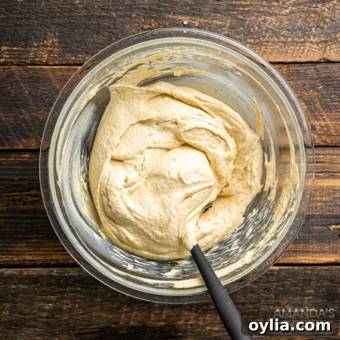 Close-up of the finished pumpkin pie dip in a mixing bowl with a spoon, highlighting its creamy, ready-to-eat texture.