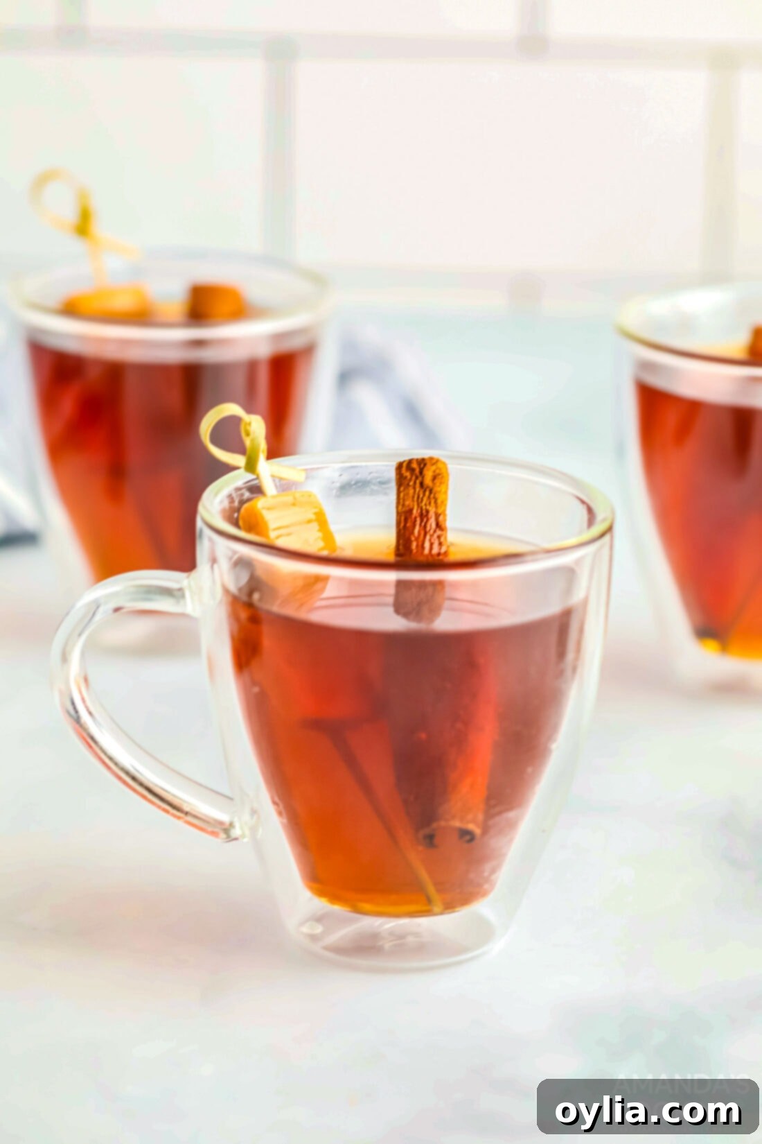 Spiked Caramel Apple Cider in glass mugs, garnished with caramel and cinnamon