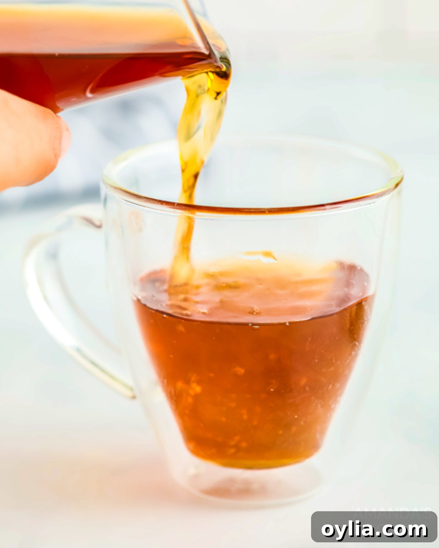 Pouring apple cider into a glass mug with whiskey and vodka, mixing the ingredients