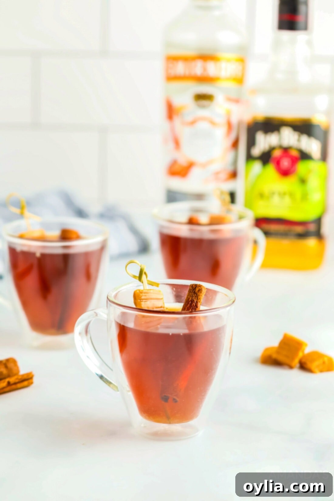 Three mugs of Spiked Caramel Apple Cider, perfectly garnished and ready for a gathering