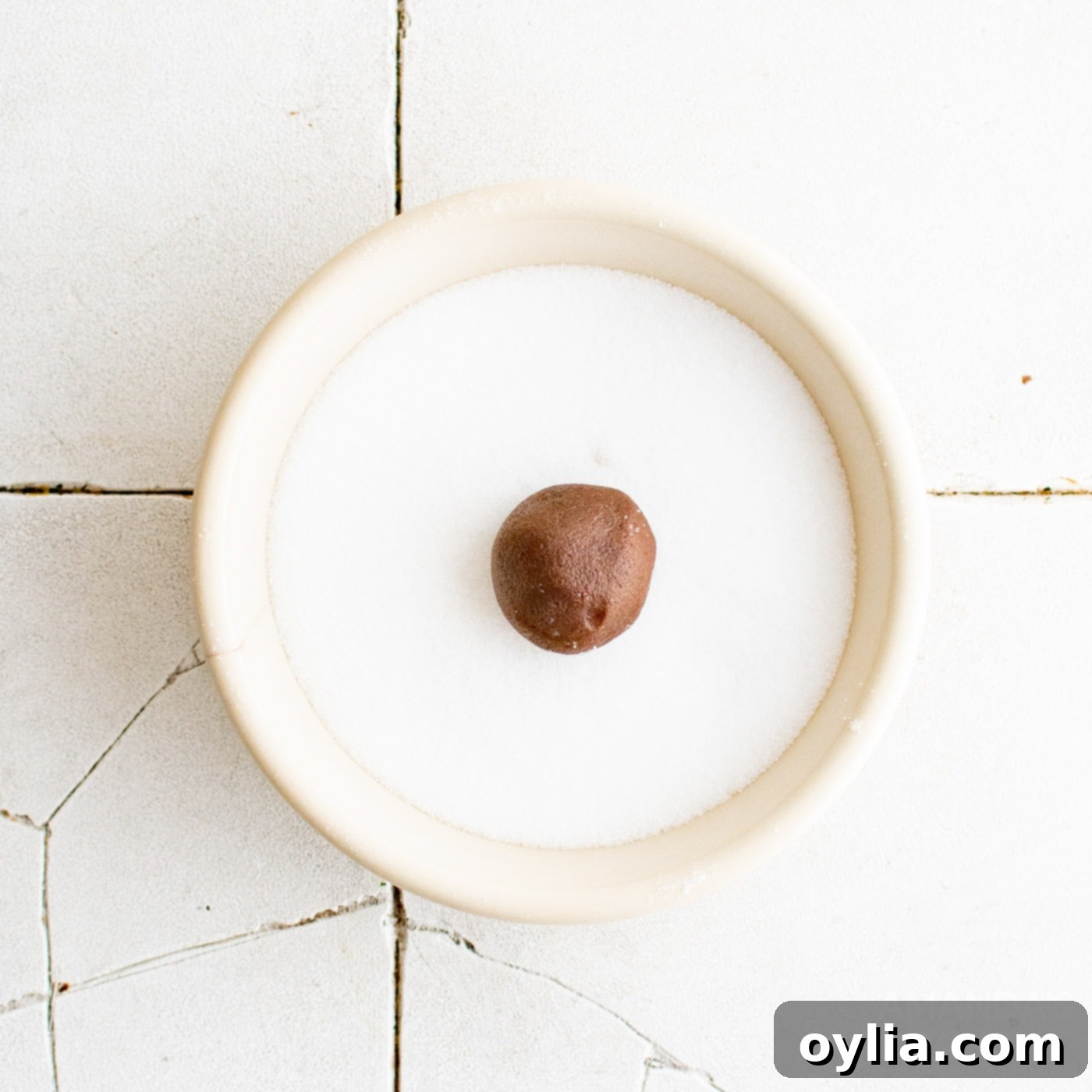 chocolate cookie dough ball in a bowl of sugar