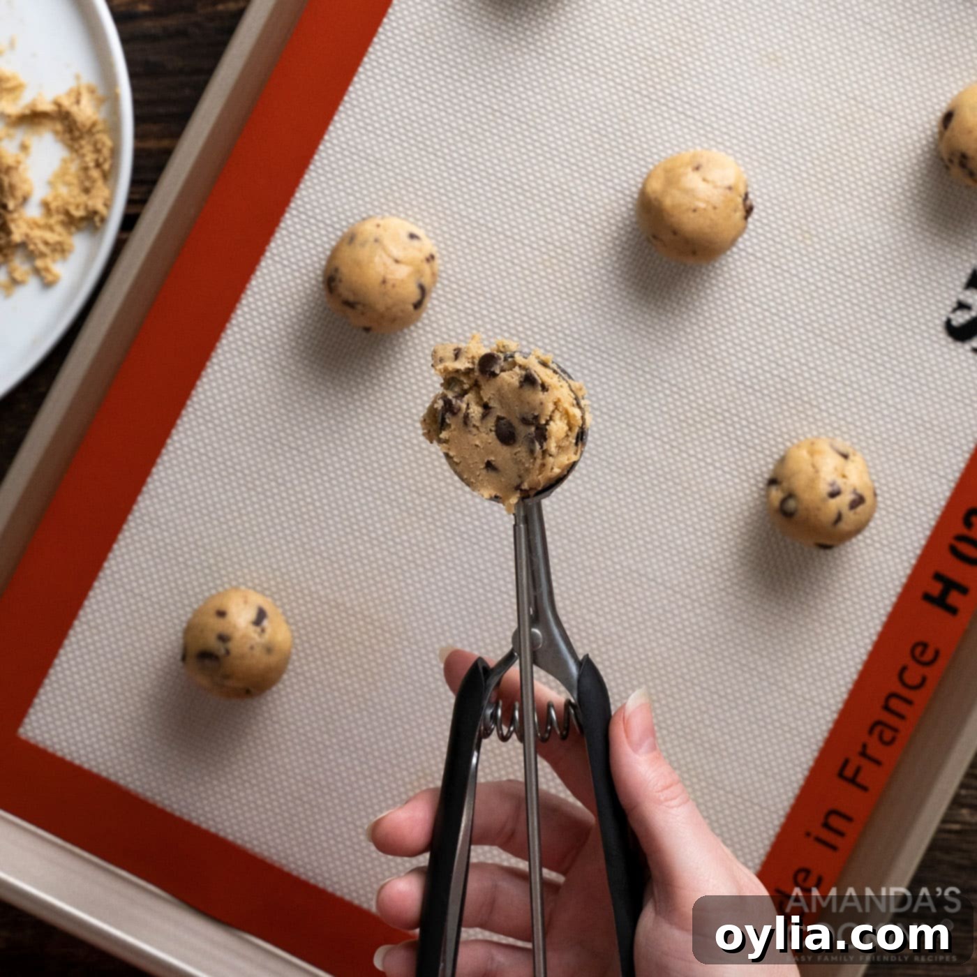 Cookie scoop portioning chocolate chip cookie dough onto a baking sheet