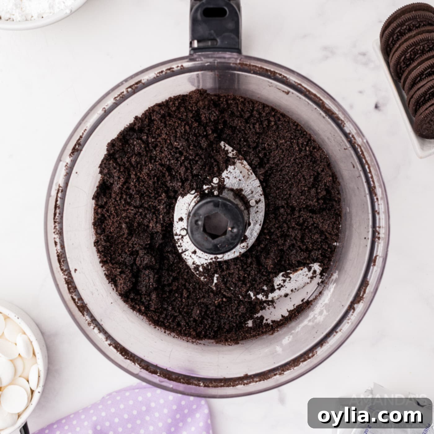 Oreo crumbs and melted butter in a food processor, creating the crust mixture.