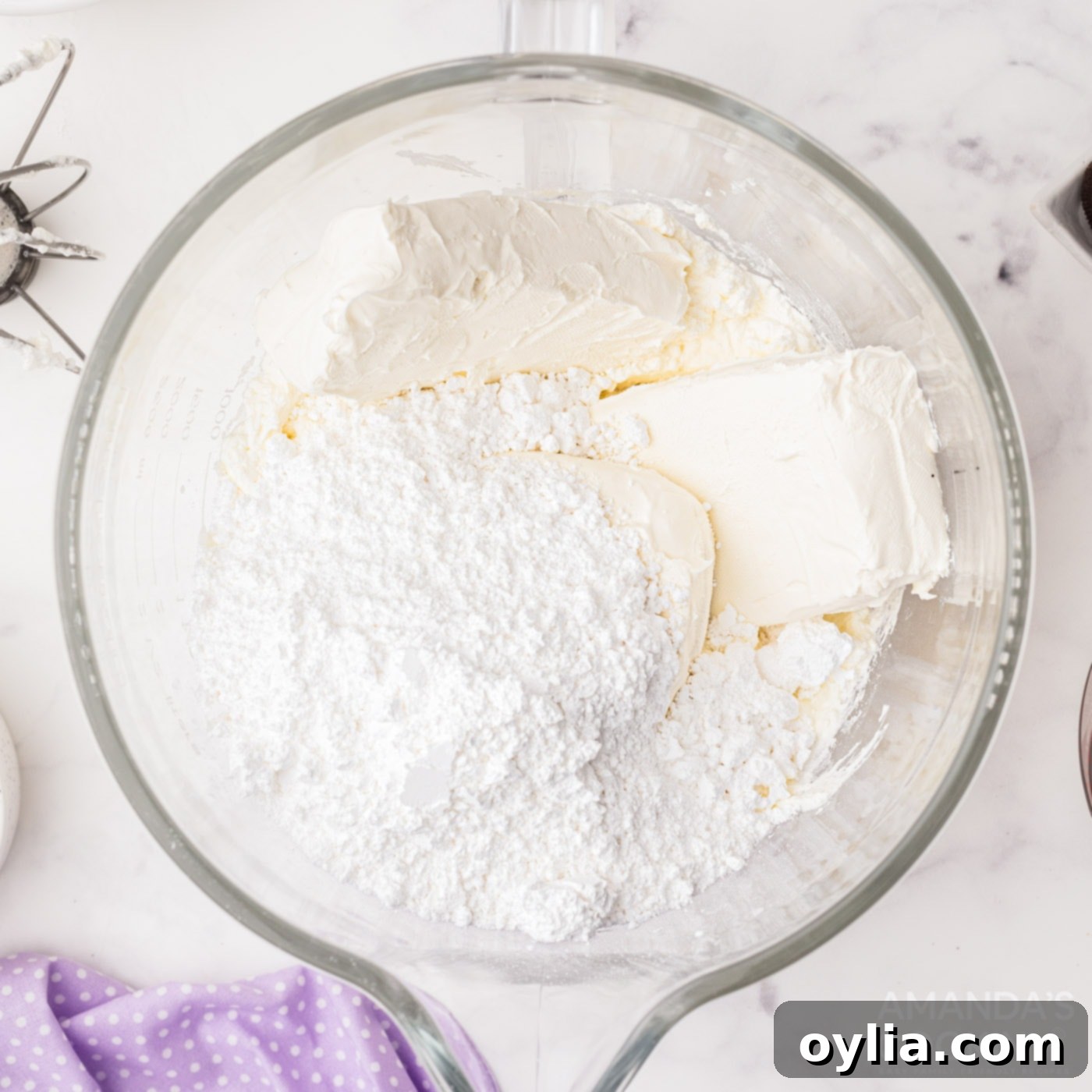 Cream cheese and powdered sugar being mixed in a large bowl for the cheesecake filling.