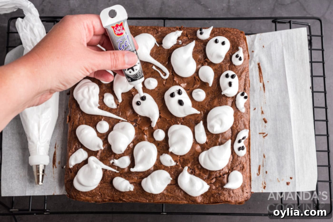 gel icing being applied to marshmallow ghosts to make eyes and mouths, bringing the characters to life.