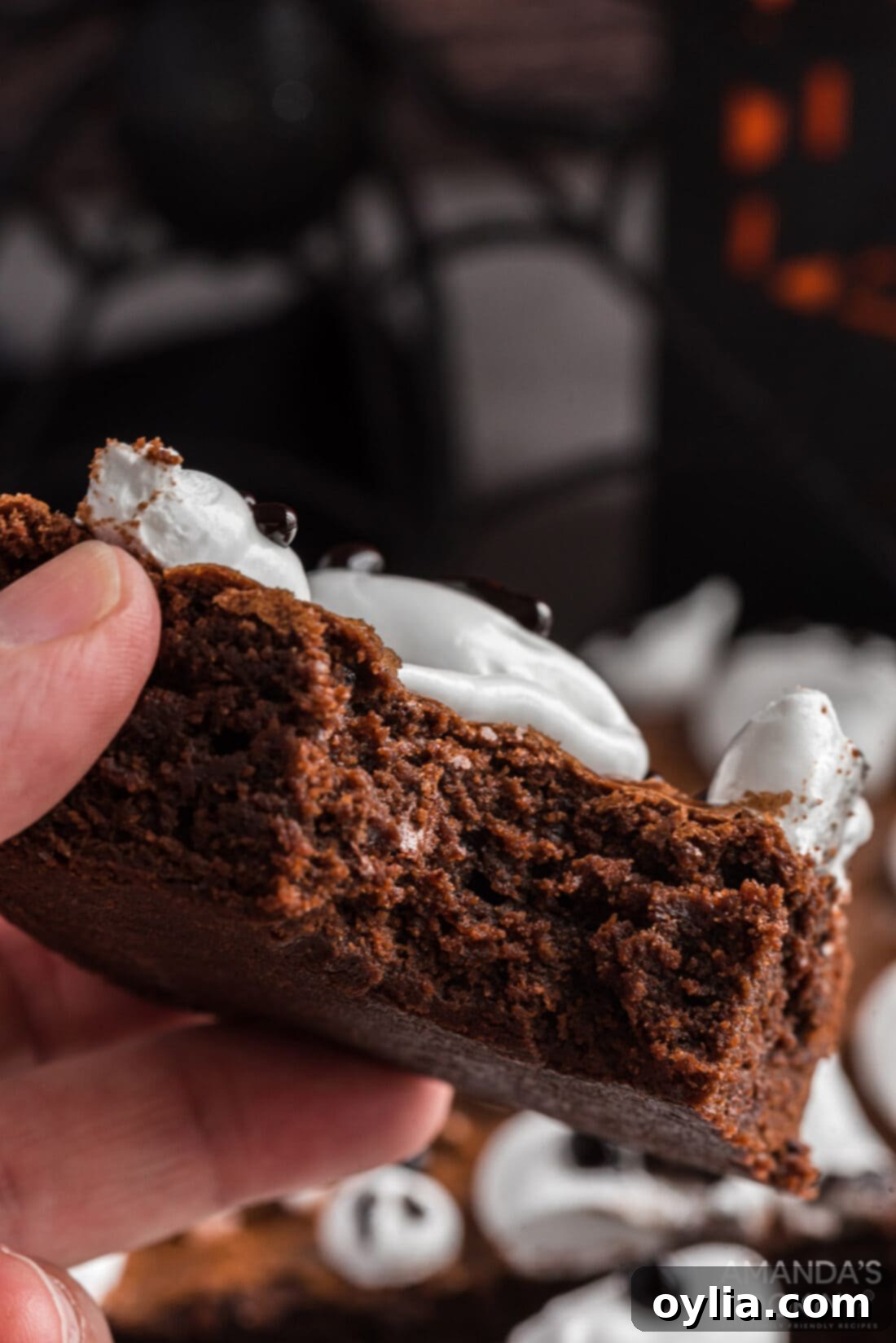 bite out of a brownie, revealing the fudgy interior and the soft marshmallow ghost topping.
