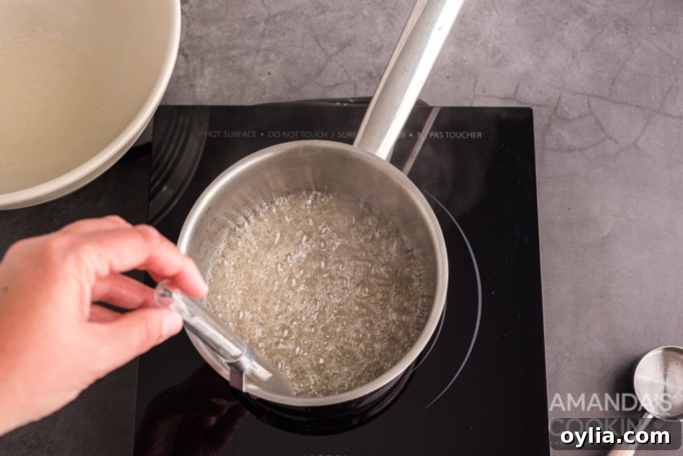 candy thermometer in a saucepan of sugar water, showing the temperature rising.