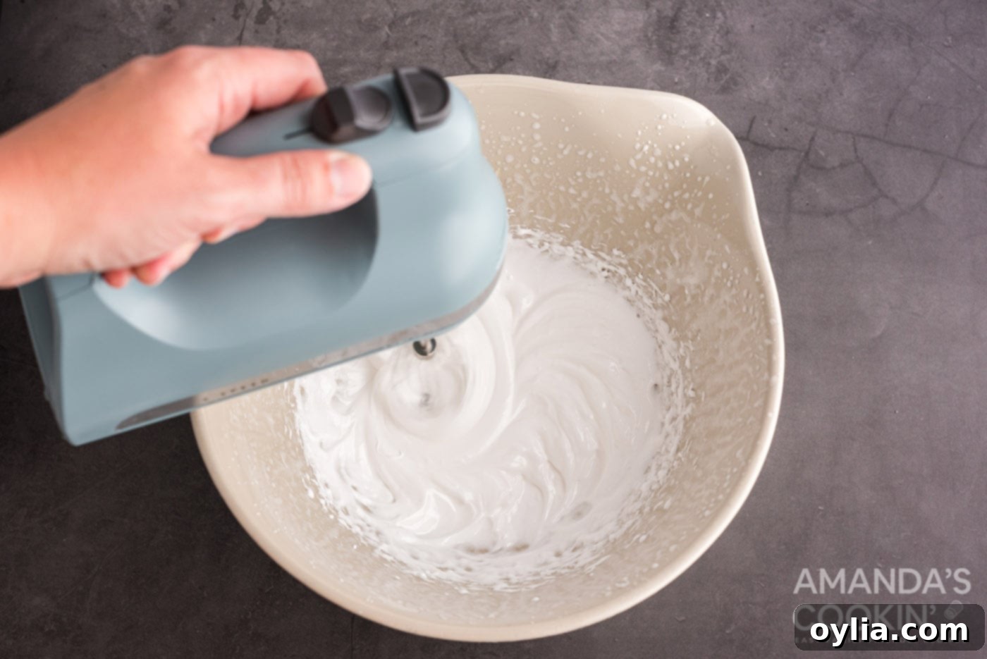 hand mixer mixing marshmallow in a bowl, showing the thick and glossy consistency.
