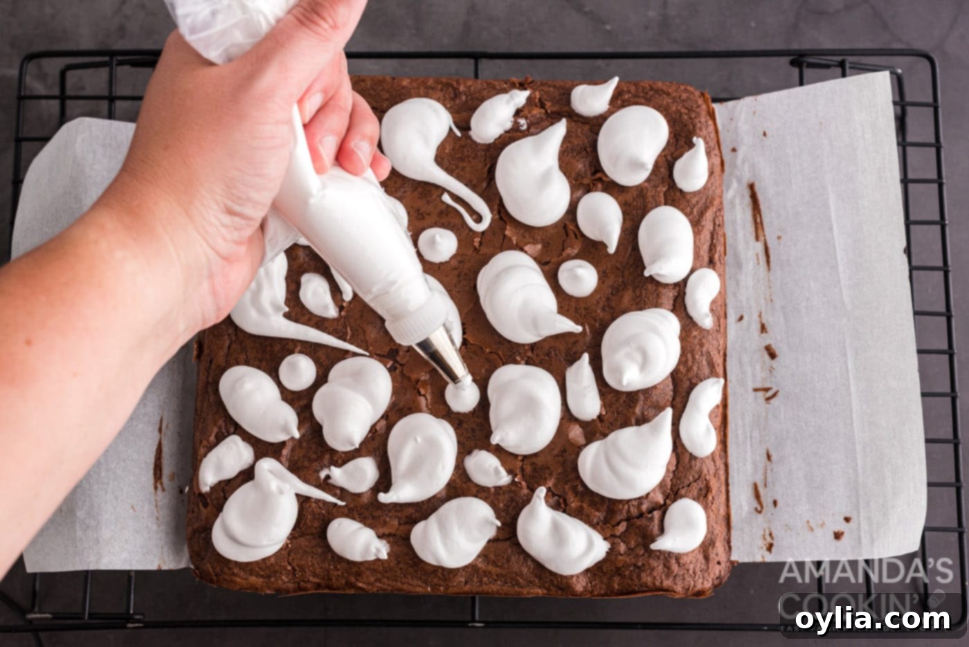 piping marshmallow ghosts onto brownies, demonstrating the technique.