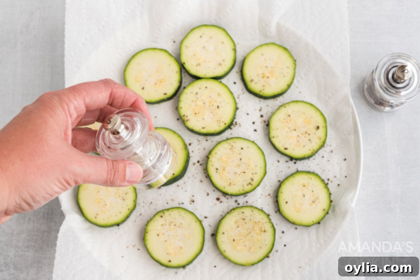 seasoning zucchini rounds with salt and pepper
